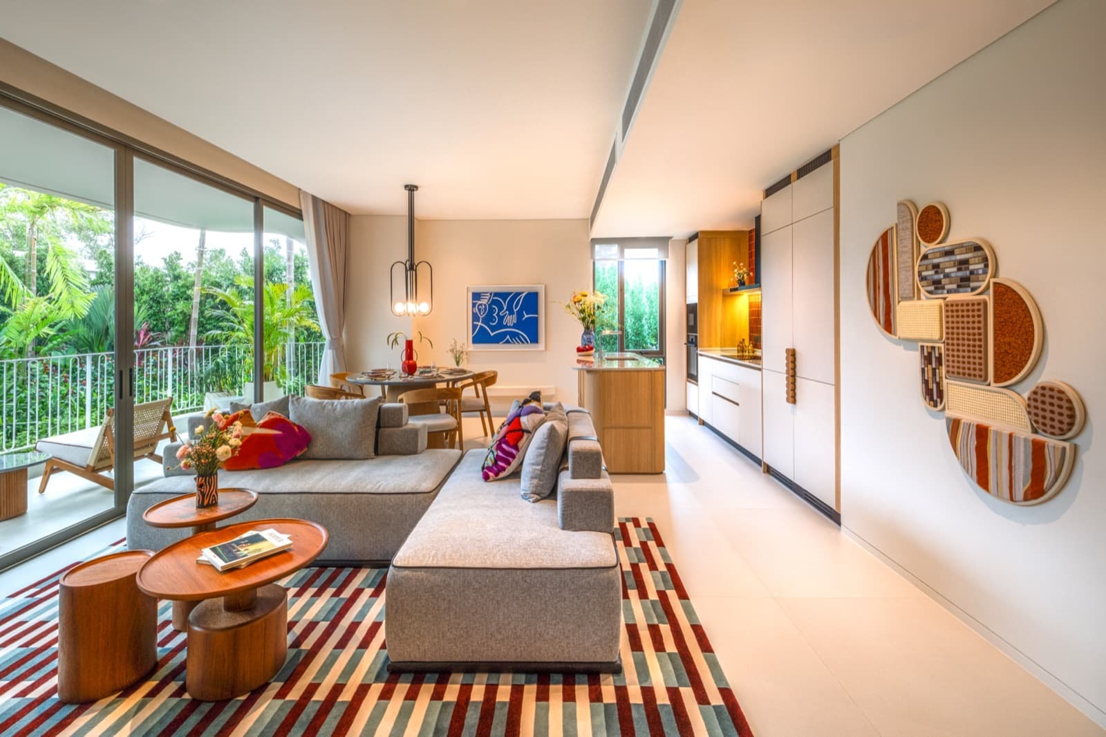 The living room and balcony of the large two-bedroom show unit at The Standard Residences, Phuket Bang Tao, with a long sofa and the kitchen on the right